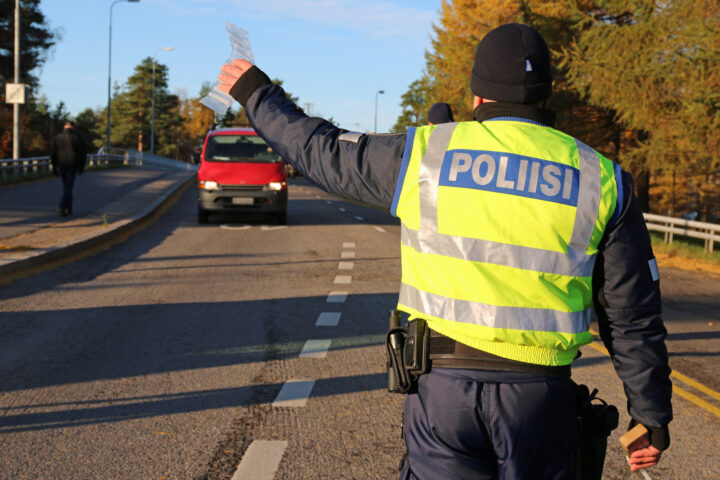 Poliisi pysäyttää punaisen pakettiauton. Poliisin kädessä on puhallusratsian tarvikkeet.